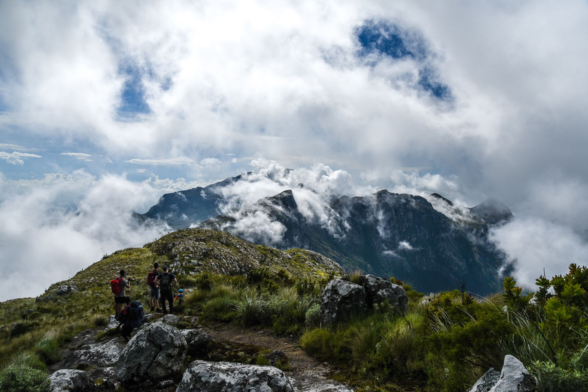 Walkers on a rocky summit above the cloud
